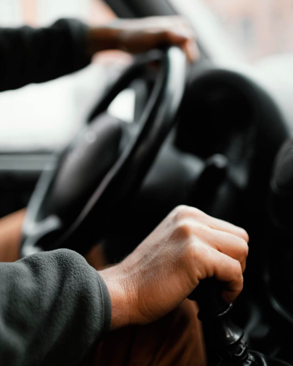 A driver's hands on the steering wheel and gear stick